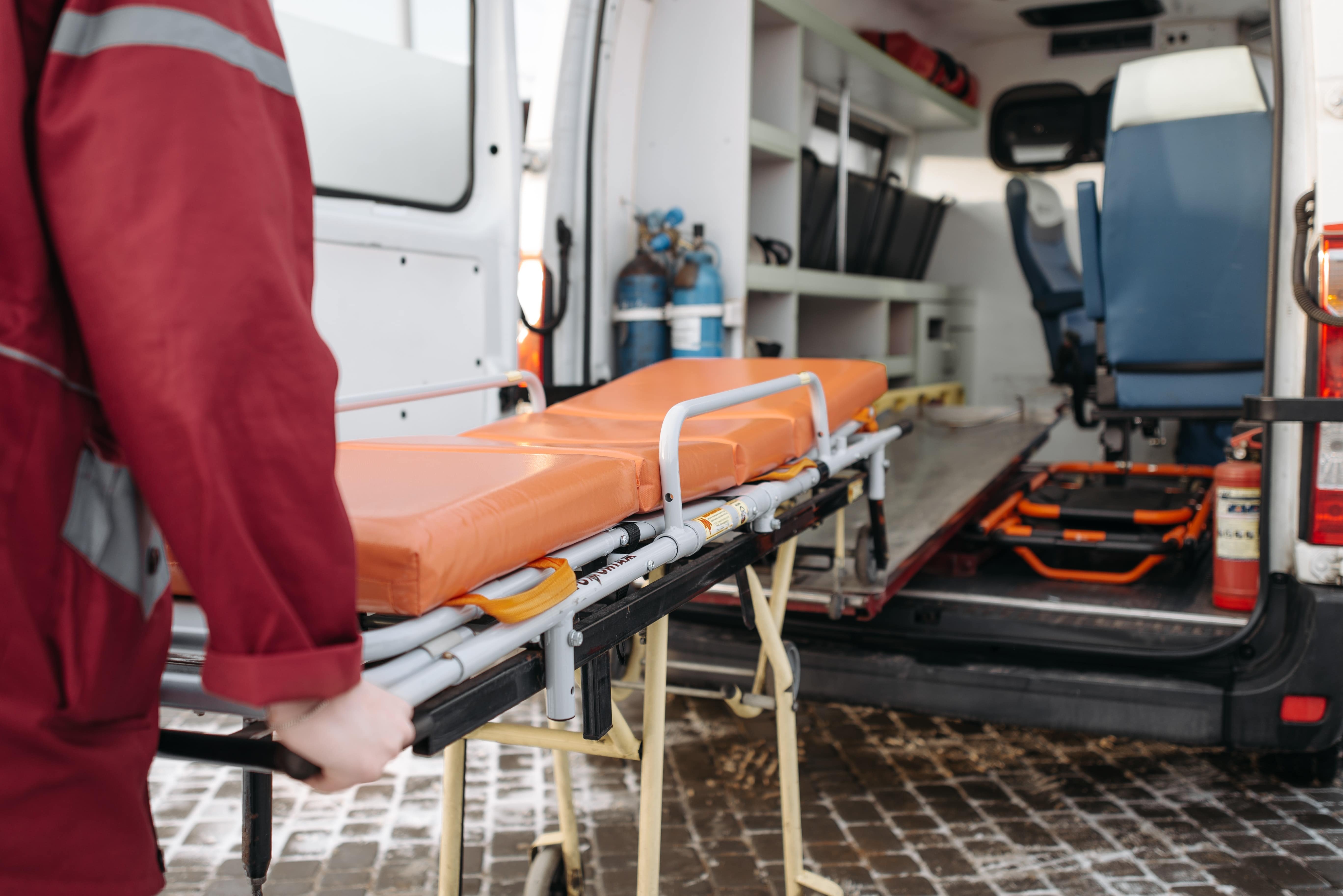 Paramedic loading a stretcher into the ambulance