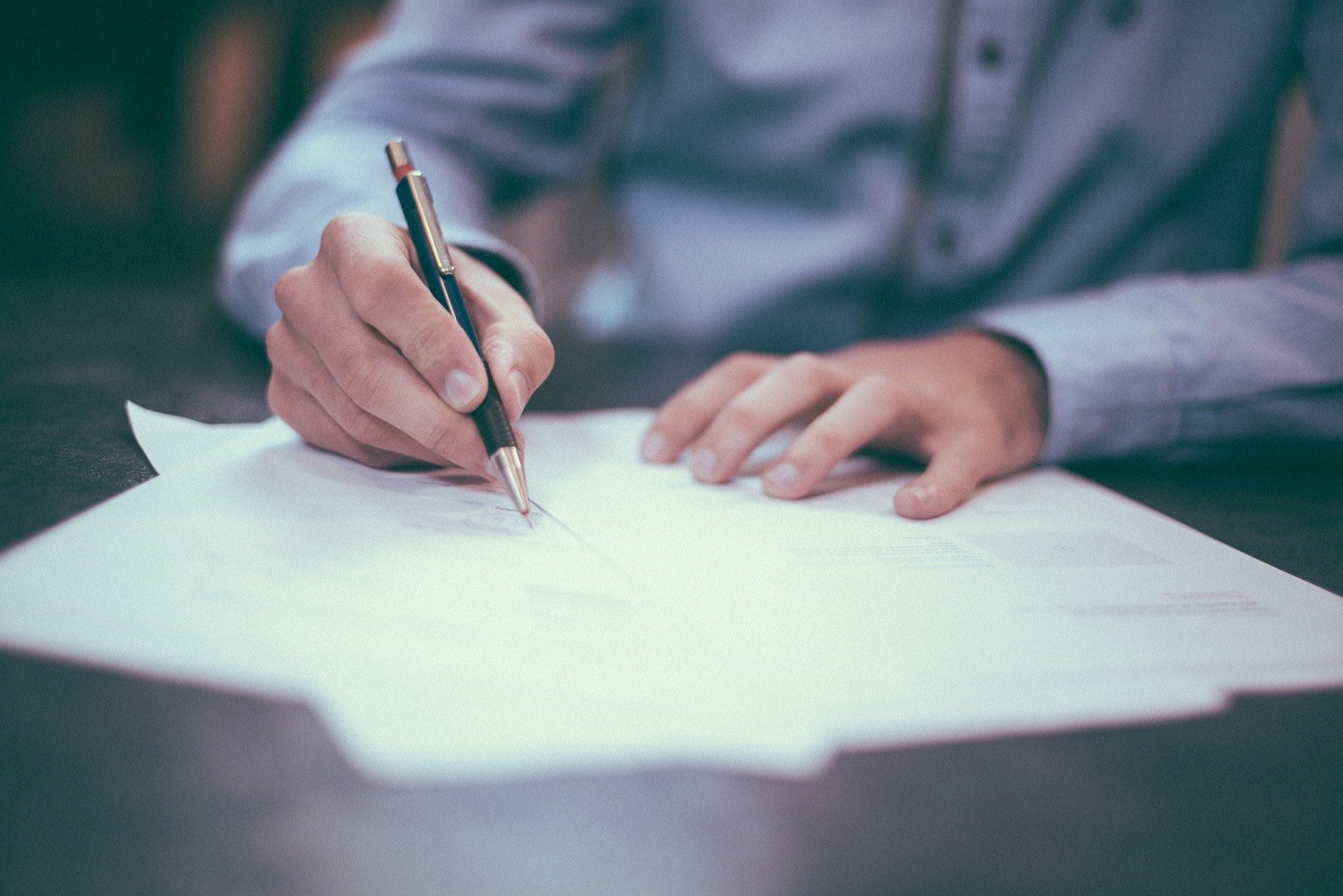 Close up of a man writing on a piece of paper