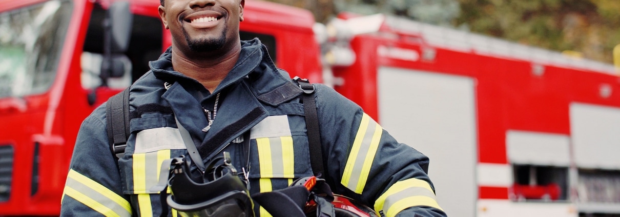 Smiling firefighter in front of a fire truck