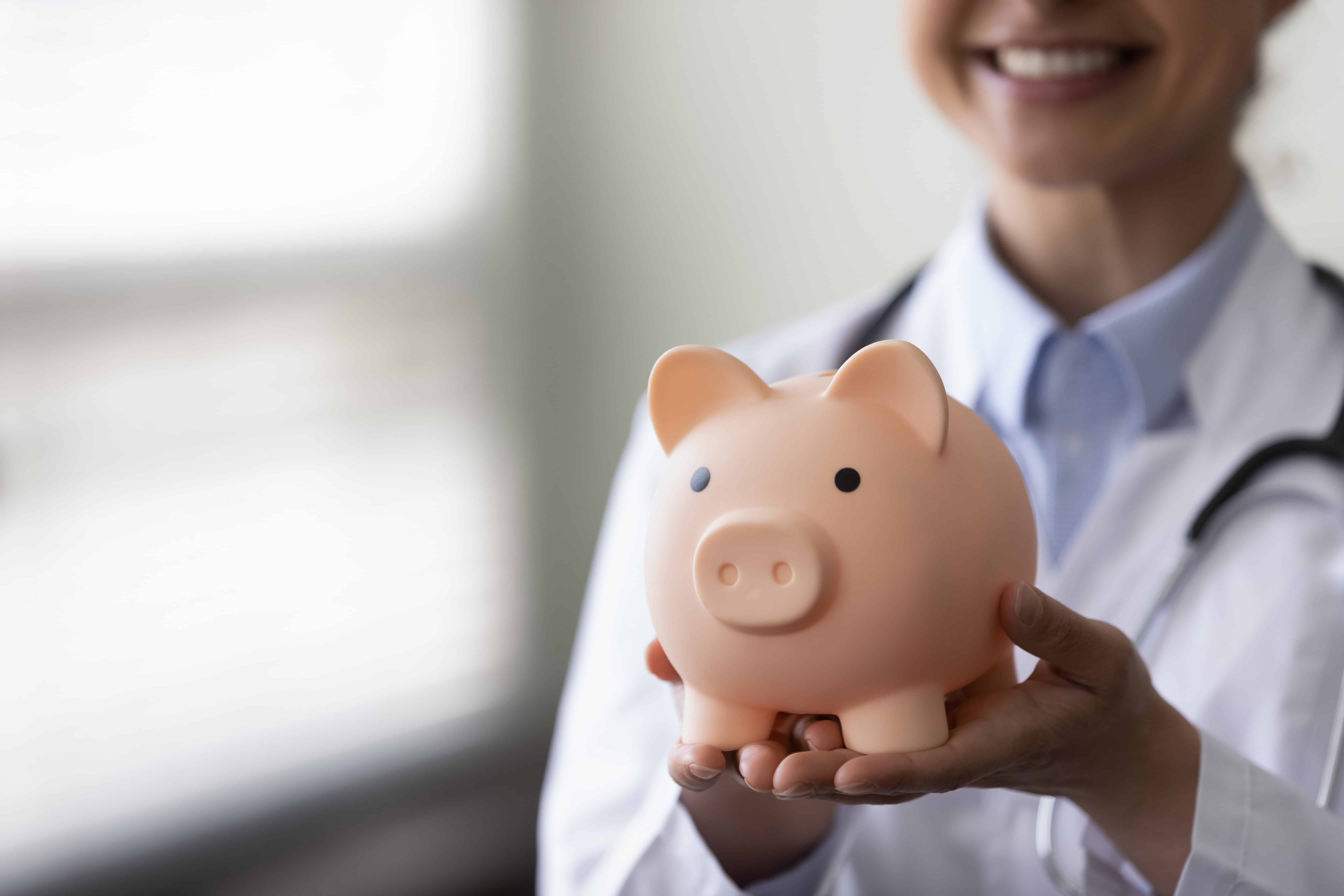 Close up of a medical professional with a piggy bank