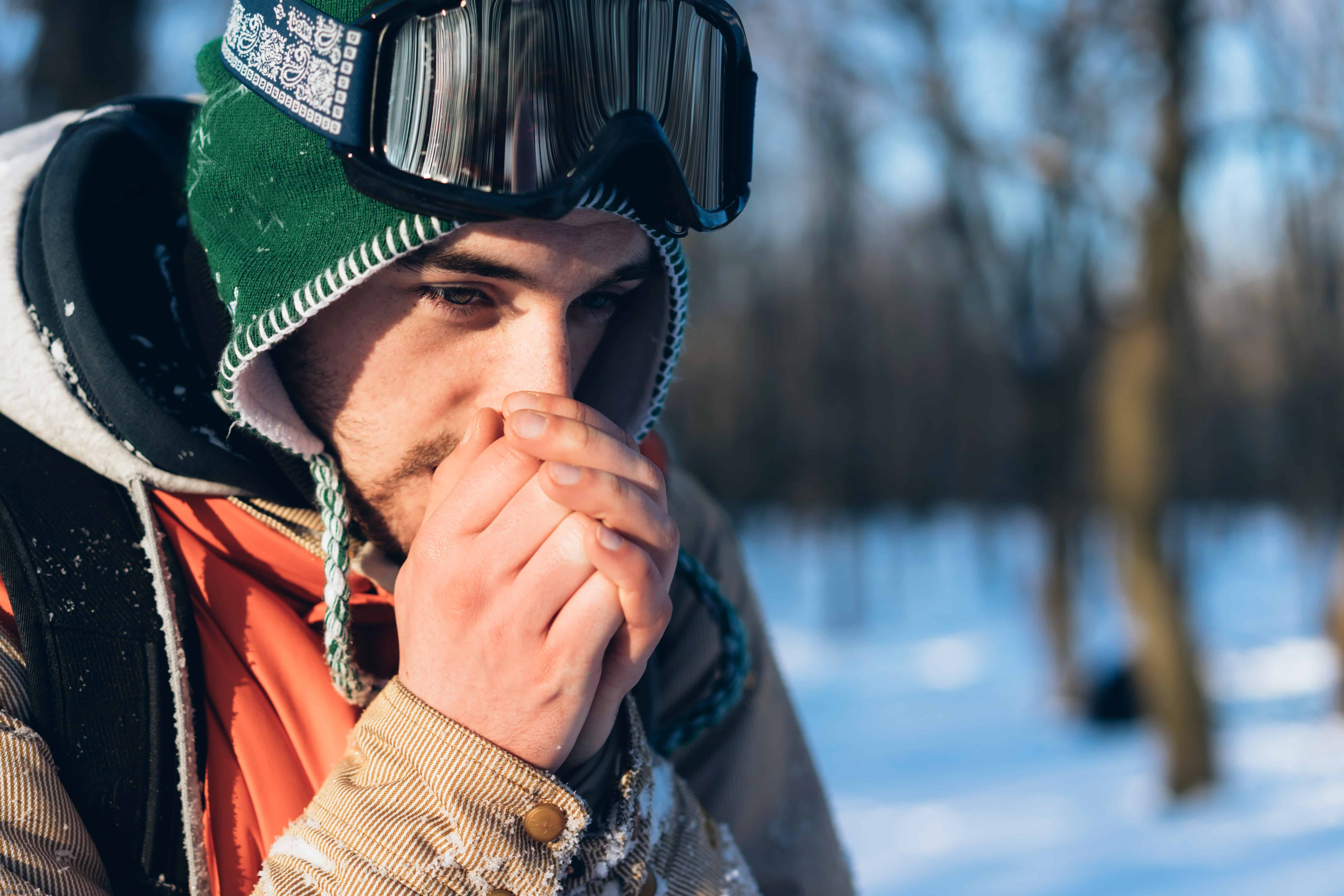 A man in ski goggles warming his hands