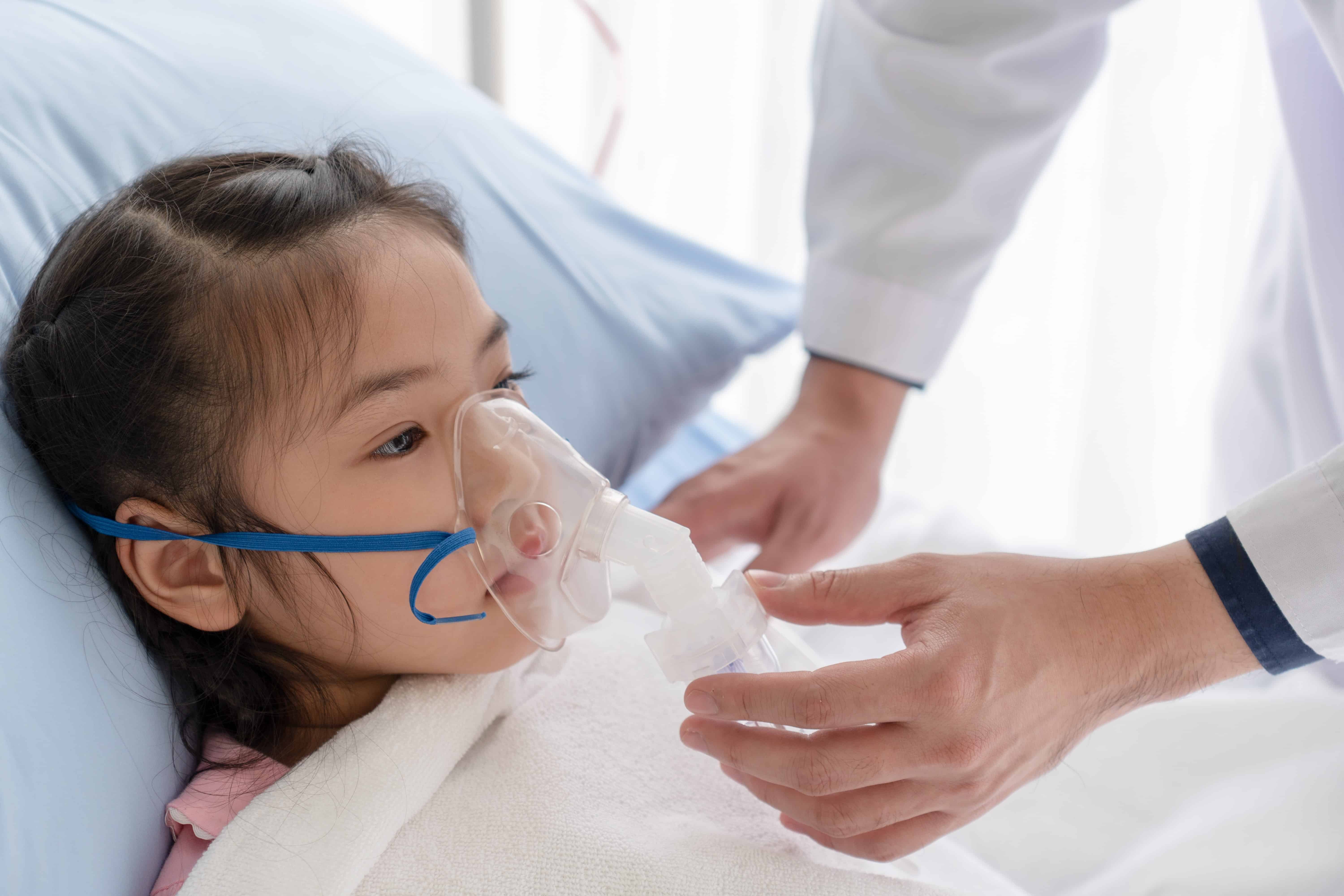 Medical professional giving oxygen to a young Asian girl
