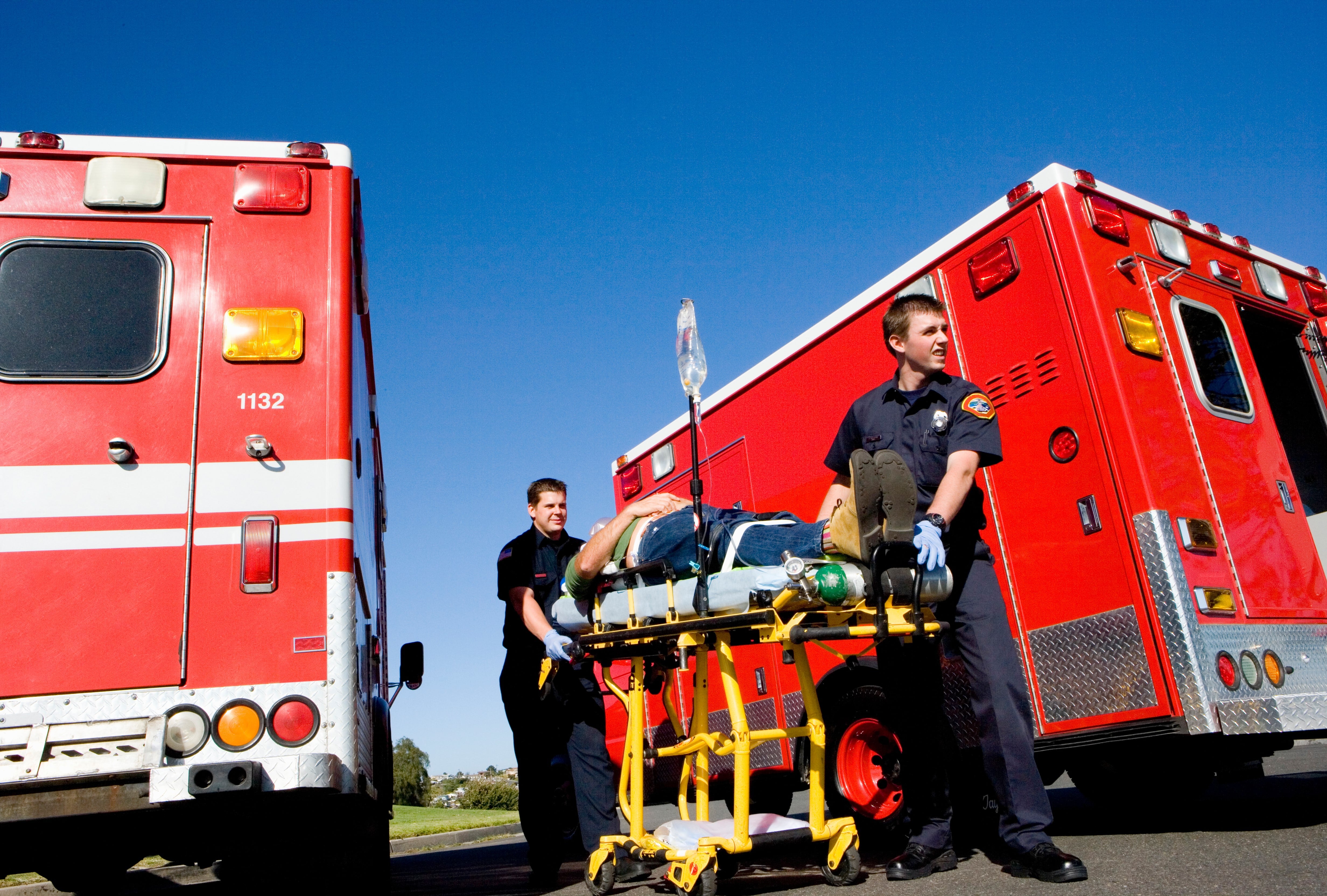 Two EMS professionals transporting a man between ambulances