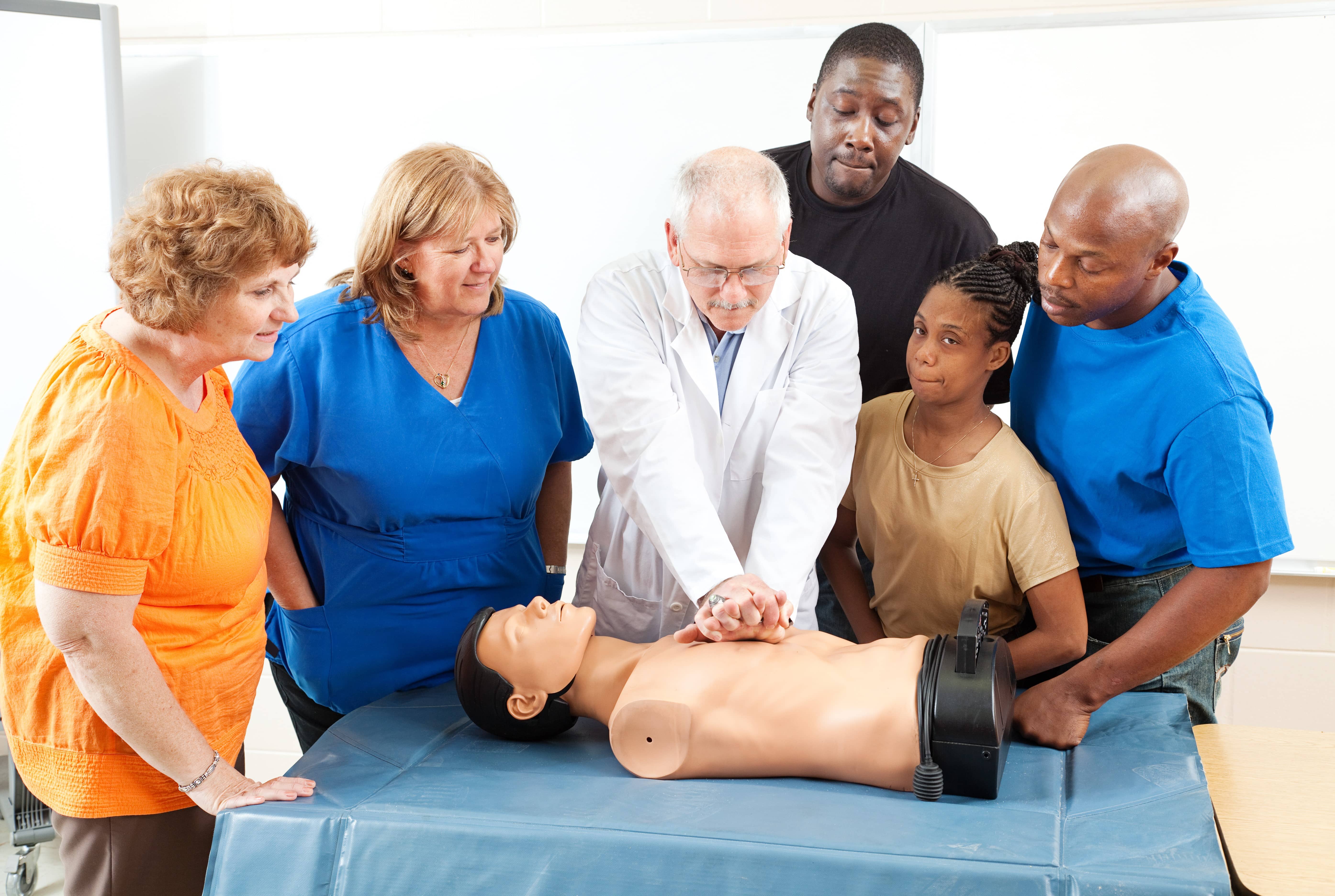 Diverse group of people learning CPR with a medical mannequin