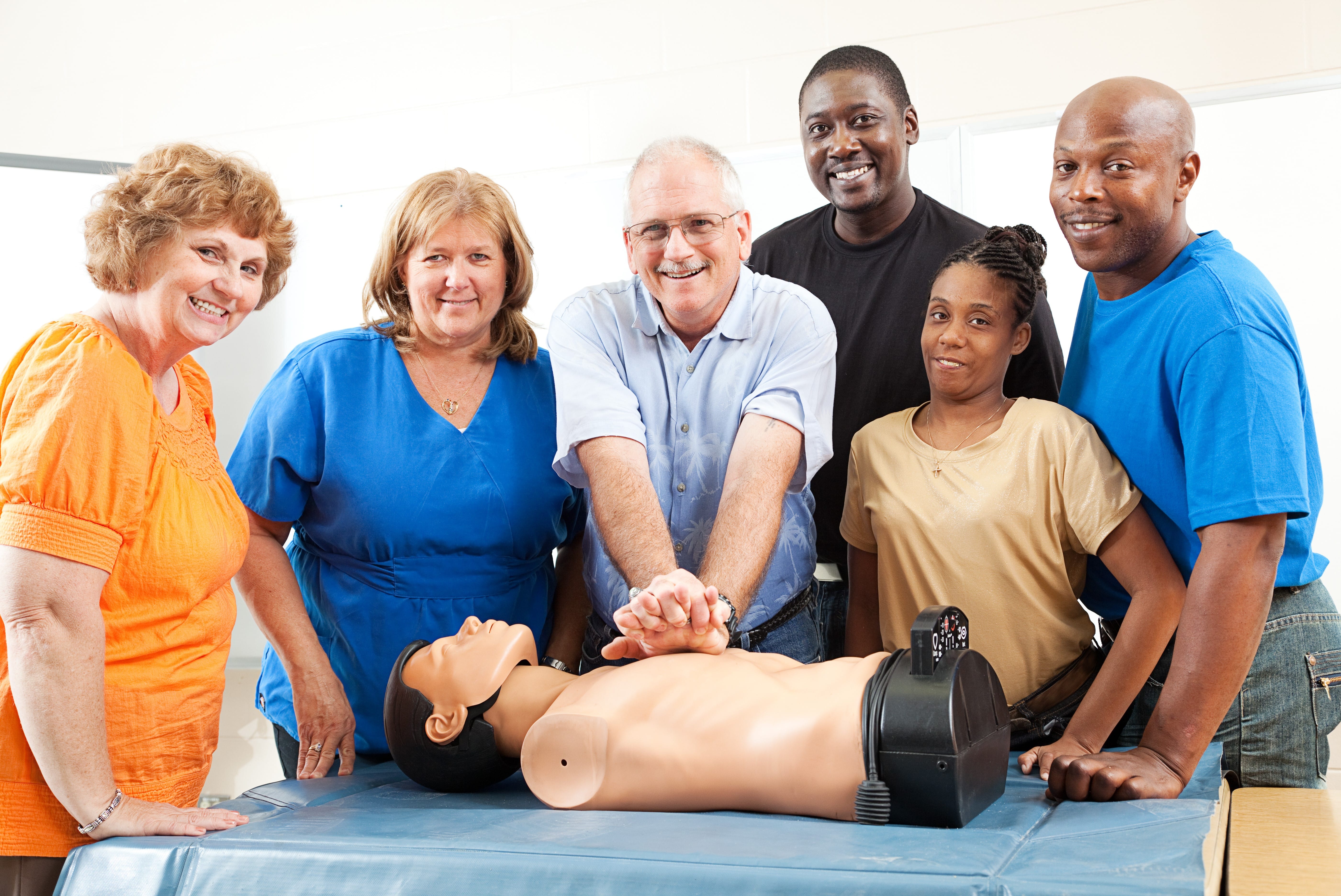 Smiling group of people with a CPR mannequin