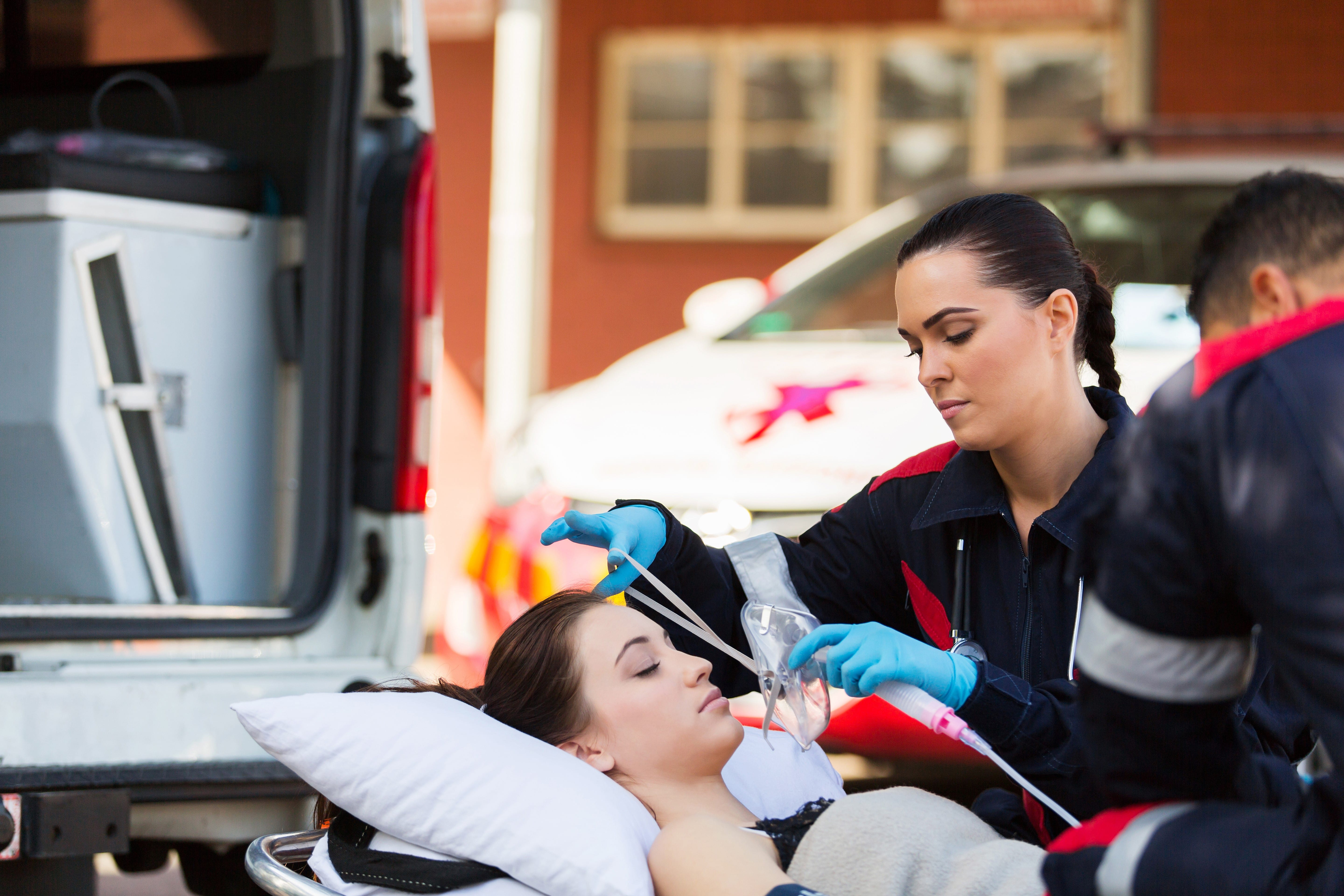 Female EMS professional placing an oxygen mask on a woman