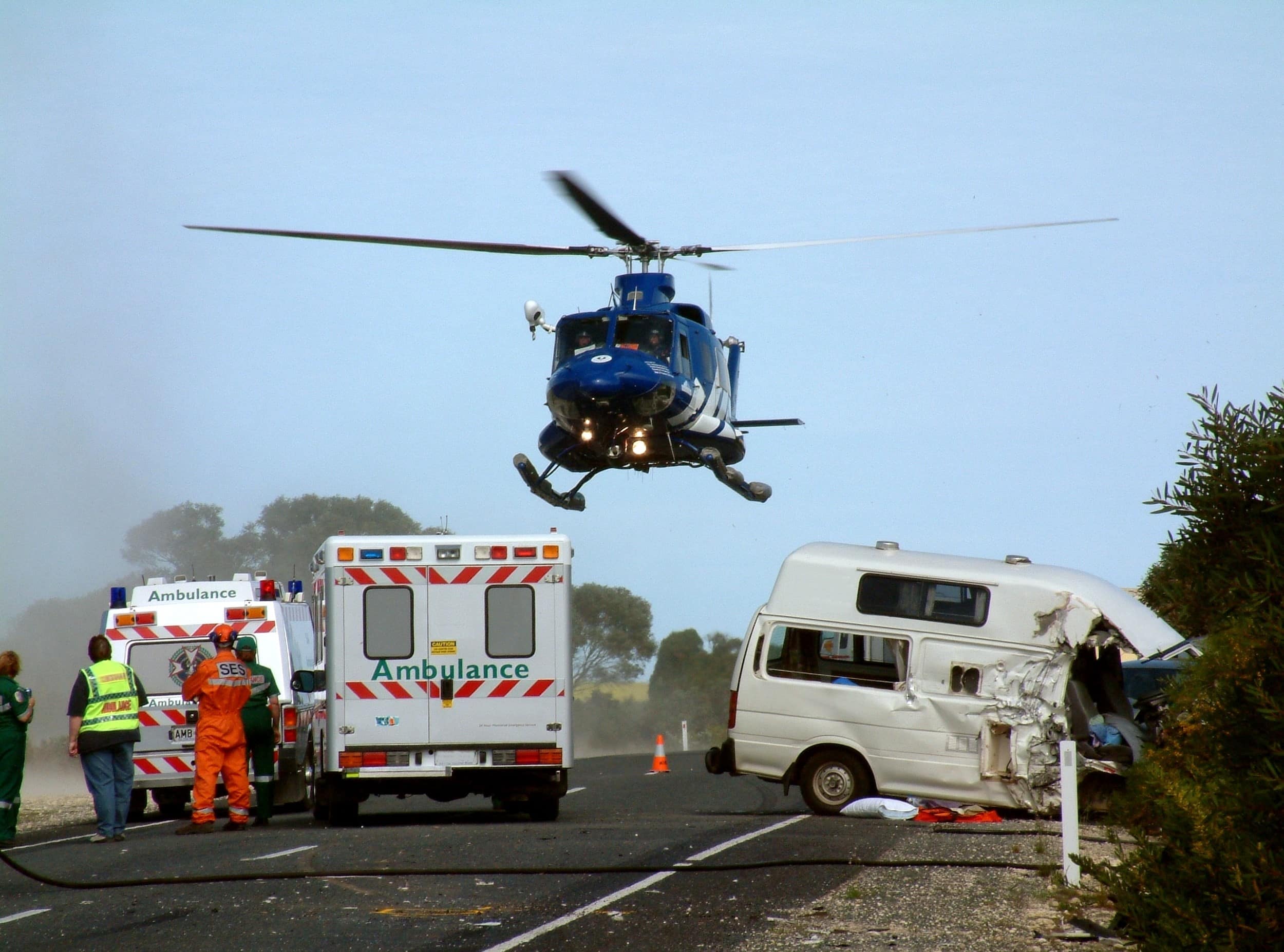 Helicopter hovering over ambulances and a crash site