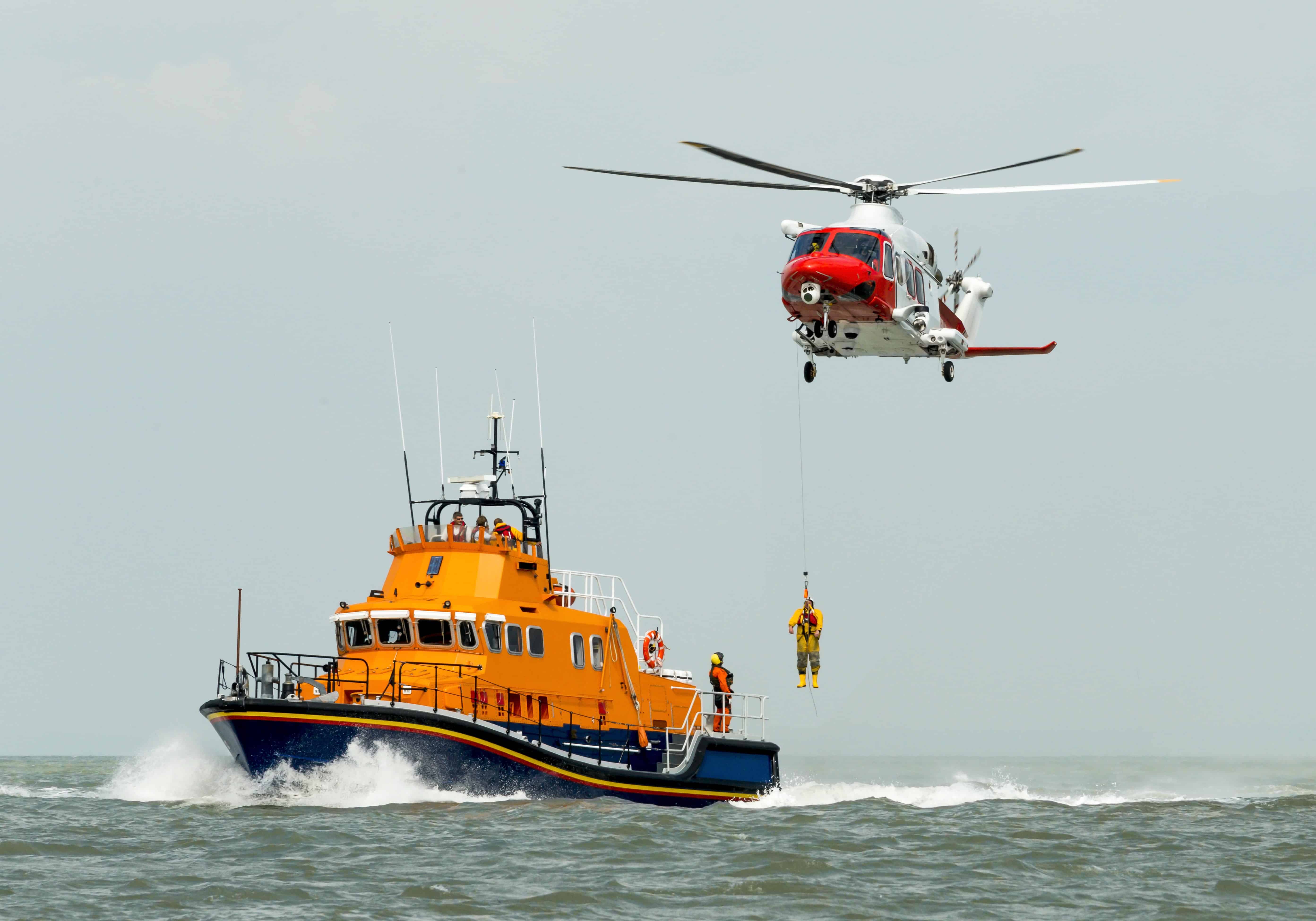 Search and rescue helicopter and ship rescuing a person