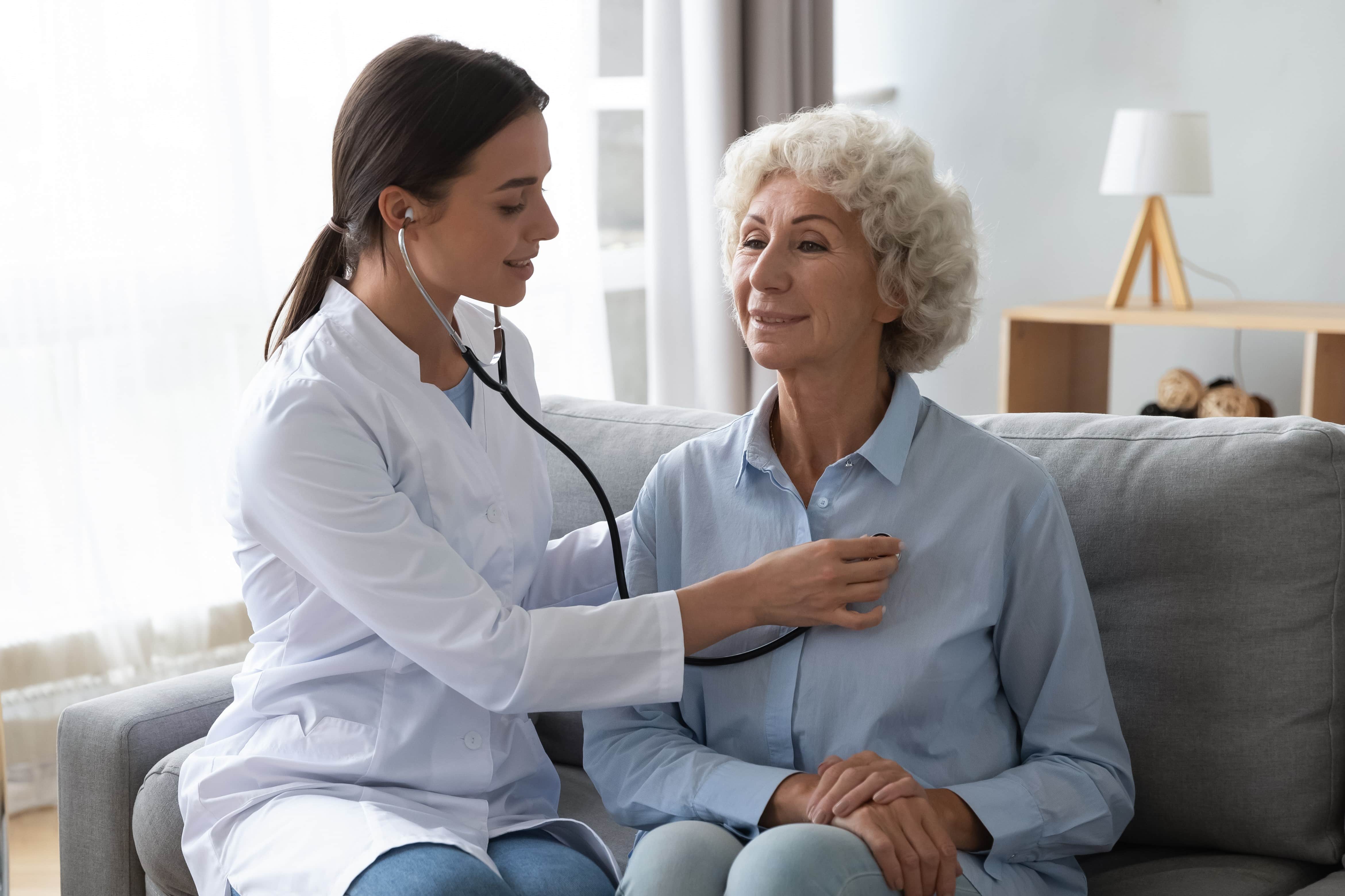 Medical professional listening to an elderly woman's heartbeat