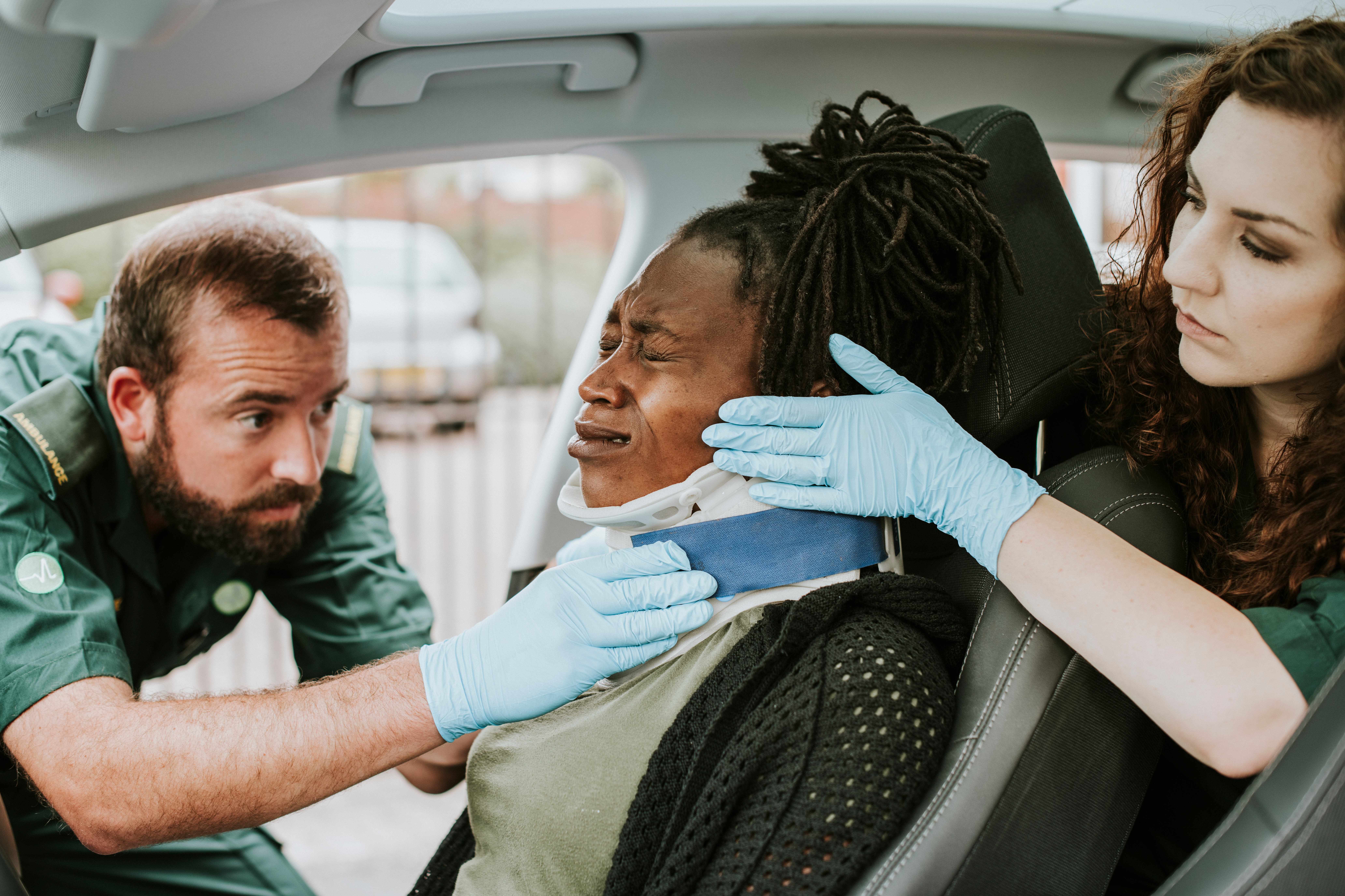 EMS professionals placing a neck brace on a woman in a car accident