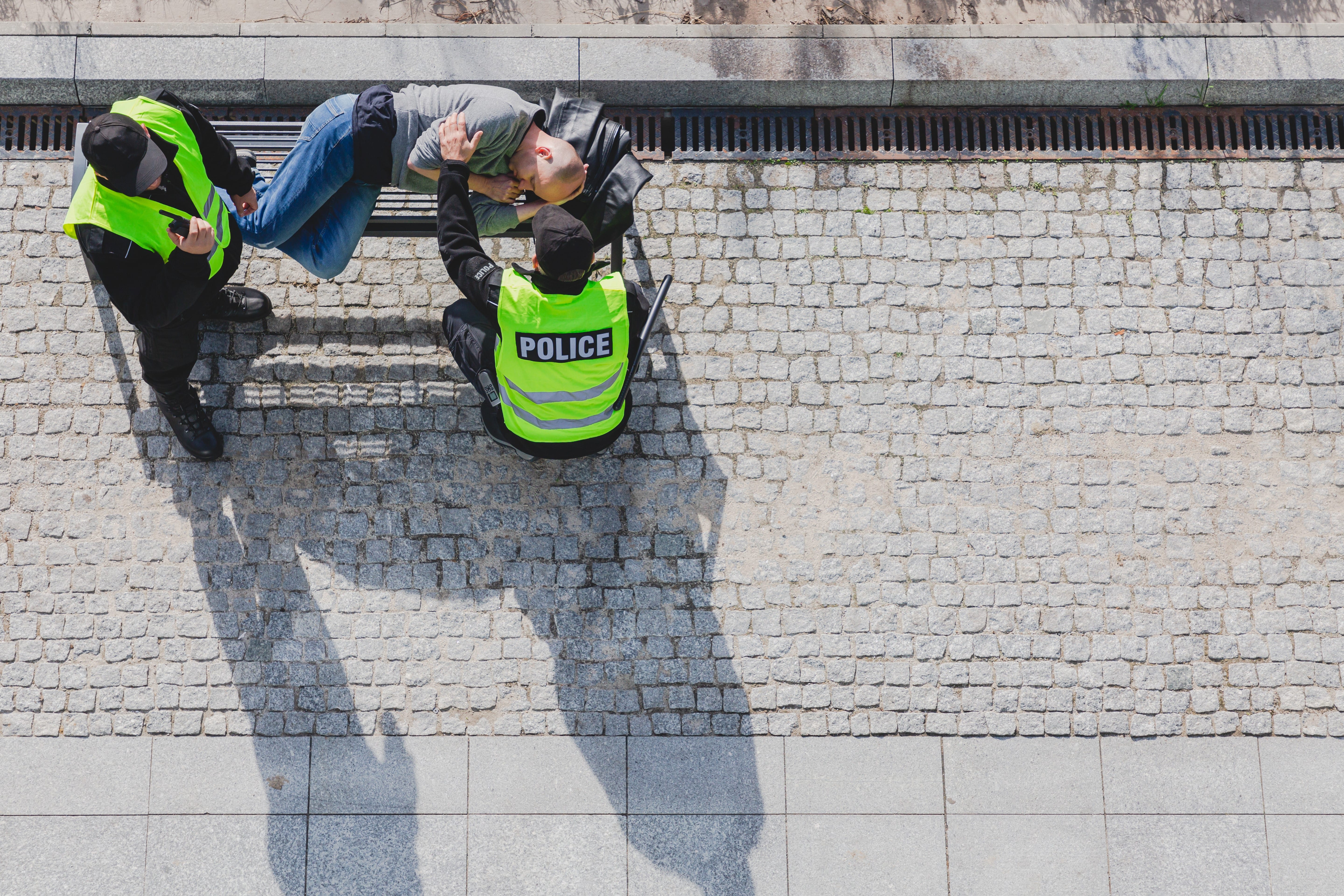 Two police officers talking to a sleeping man on a bench