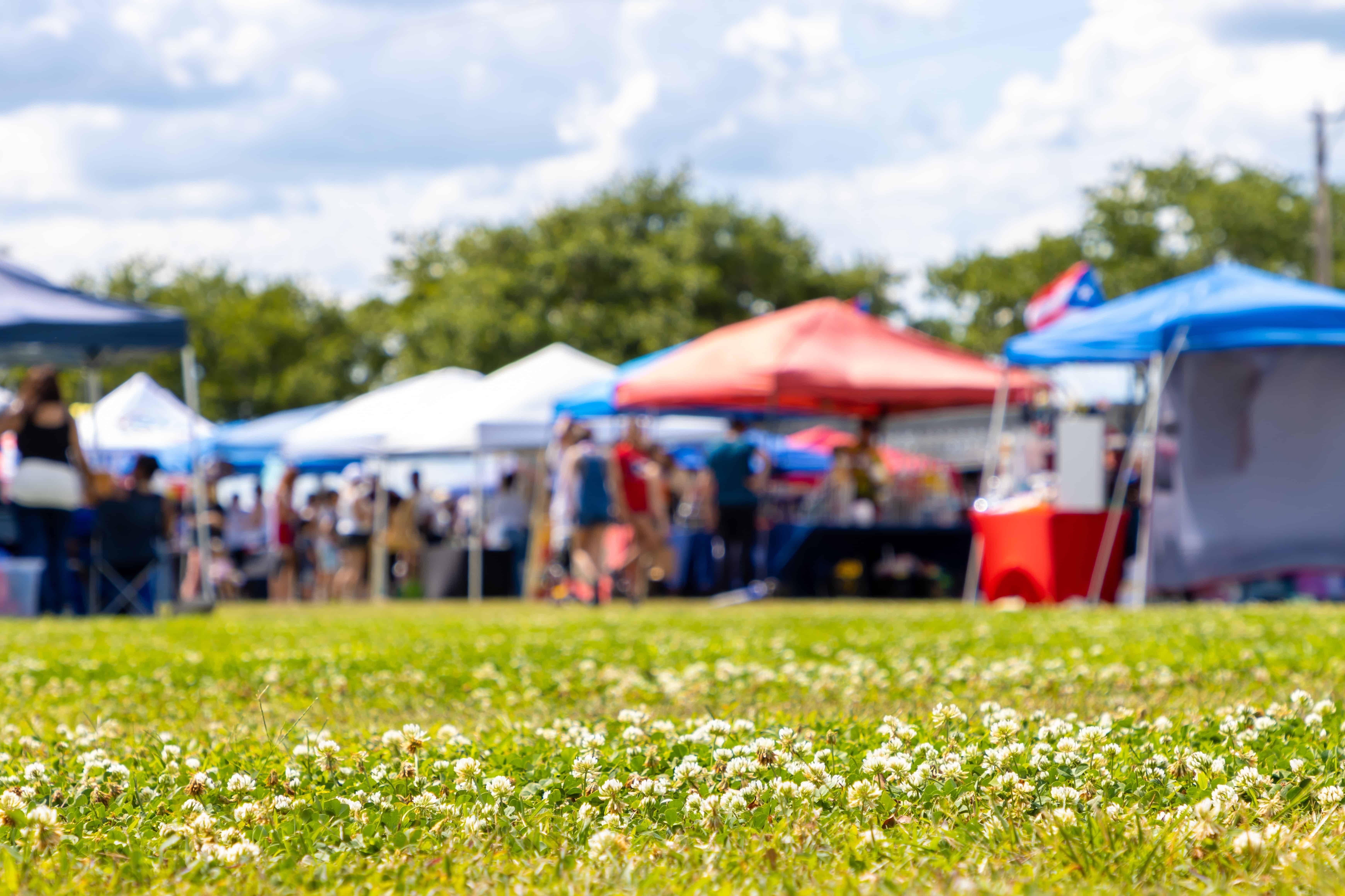 Blurred image of grass and stalls at a health fair