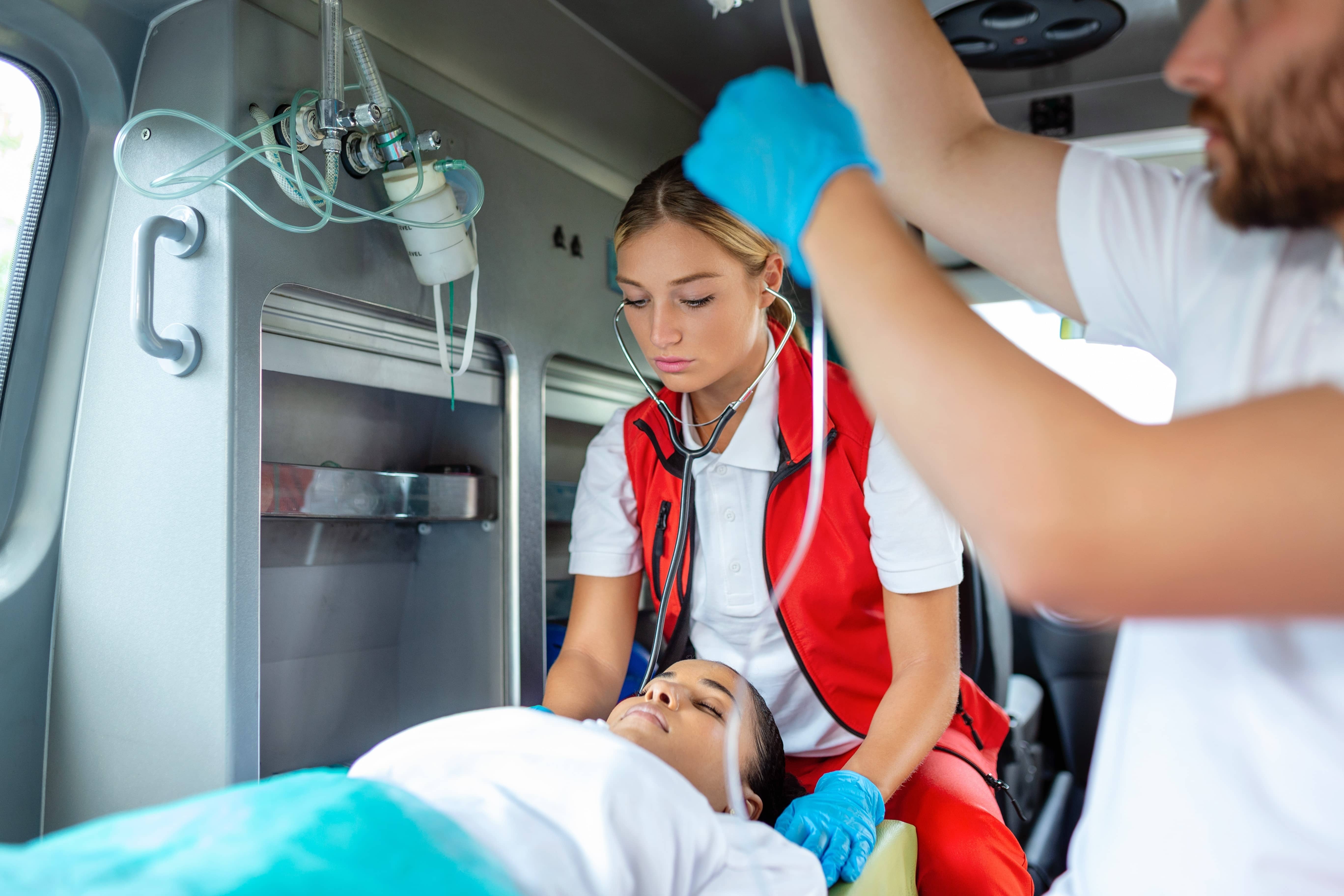 Two EMS professionals transporting a woman in an ambulance