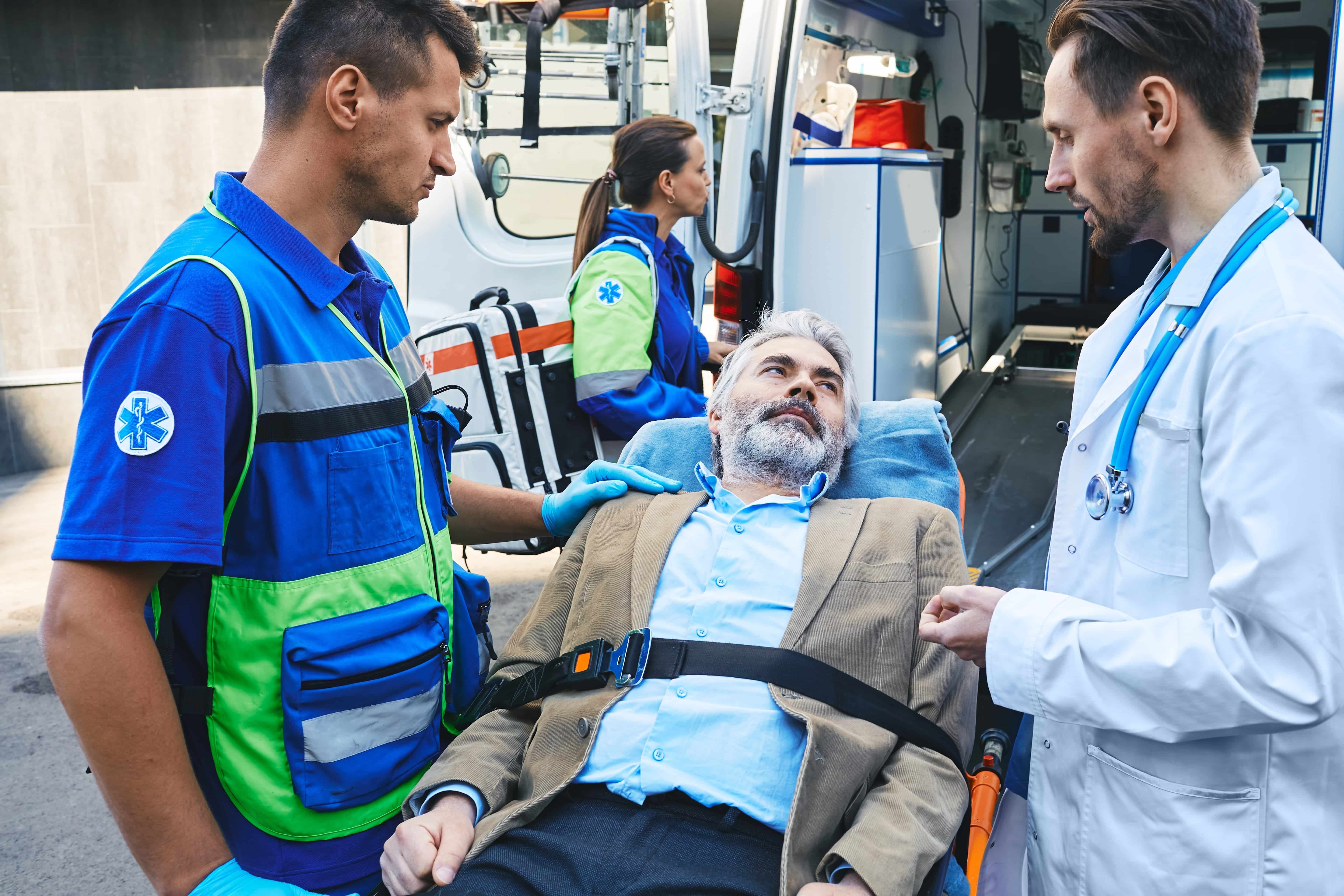 EMS team and a doctor consulting with a man on a stretcher