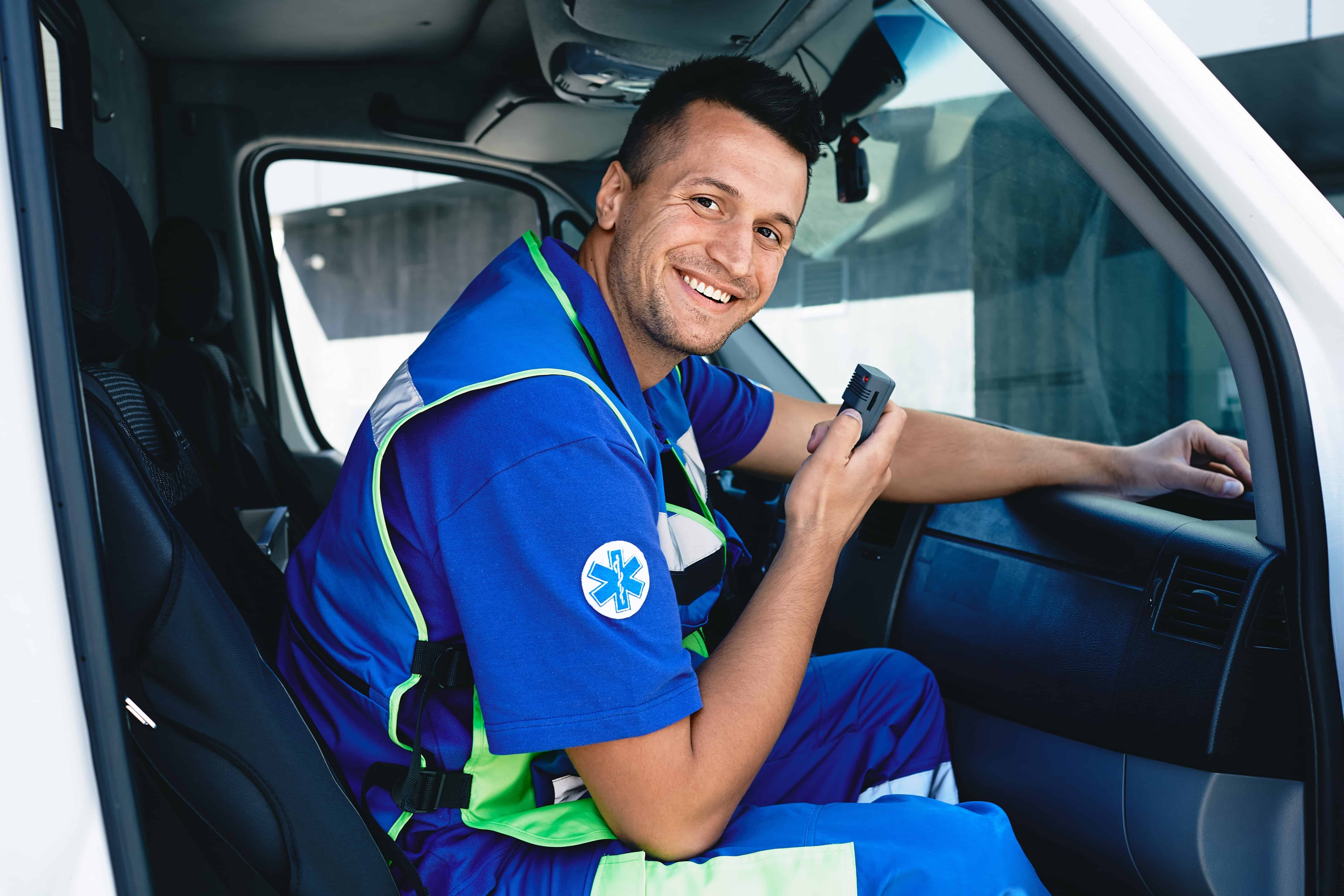Male EMS professional smiling in an ambulance with a radio