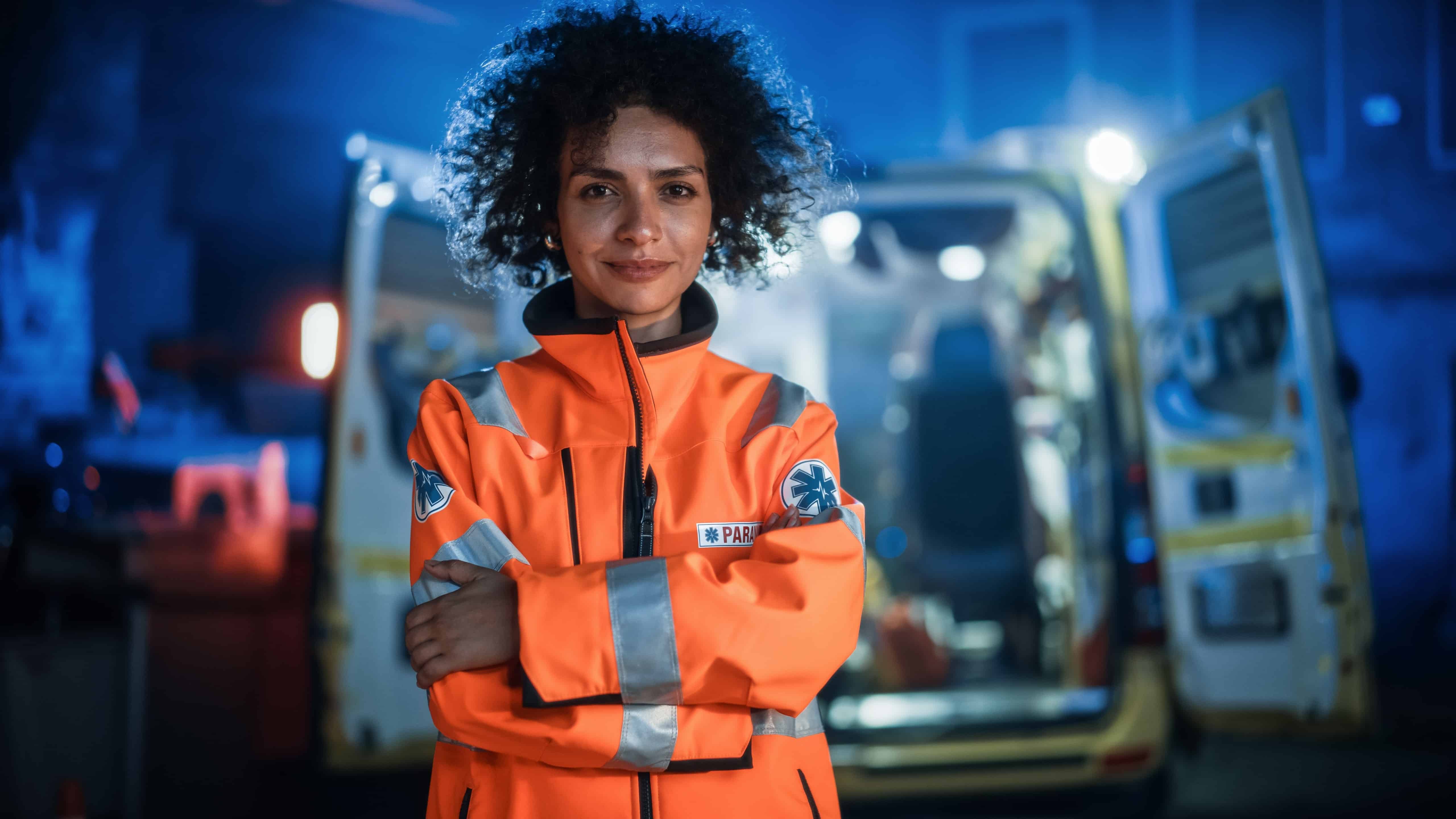 African-American EMS professional standing in front of an ambulance