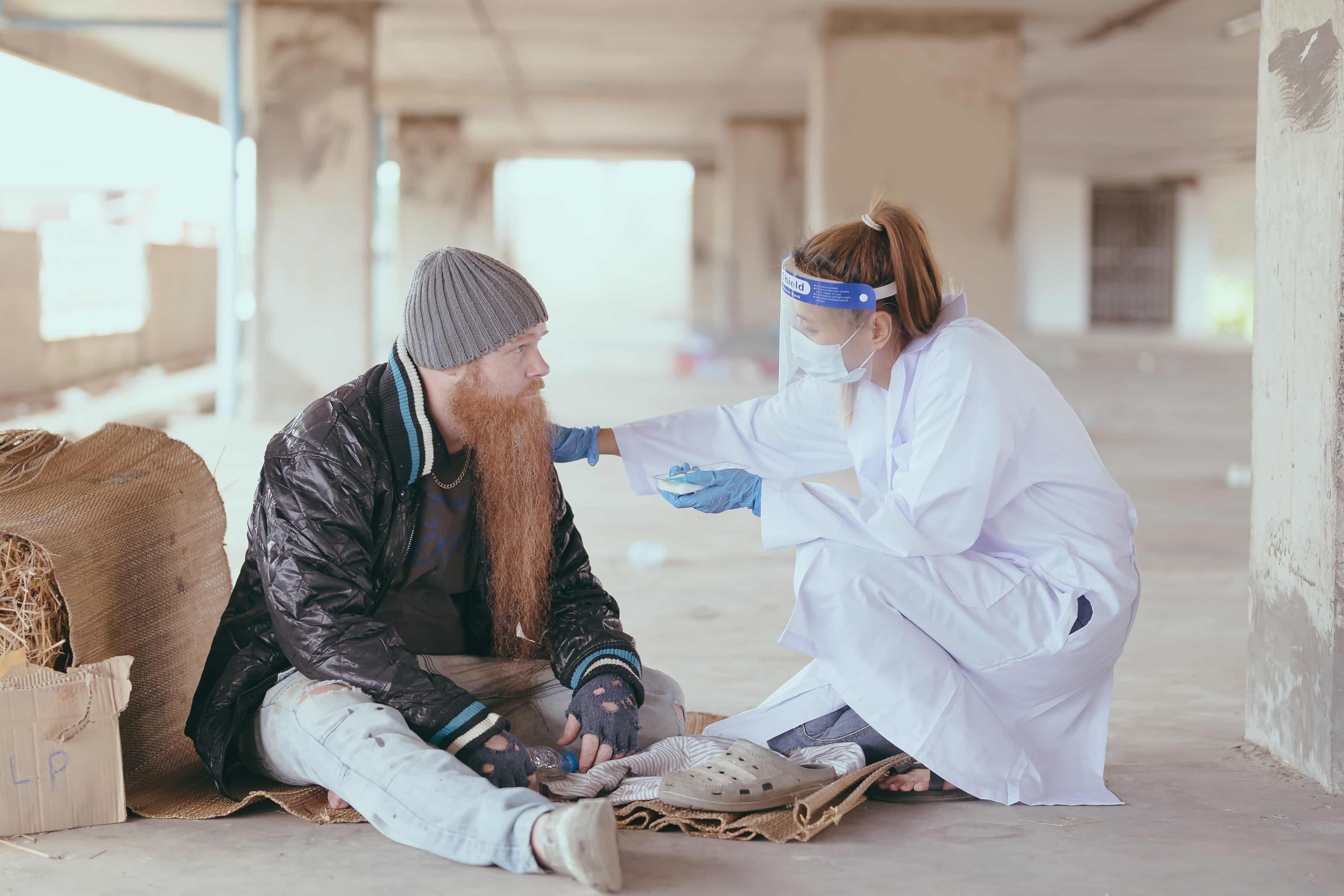 Medical professional helping a homeless man on the street