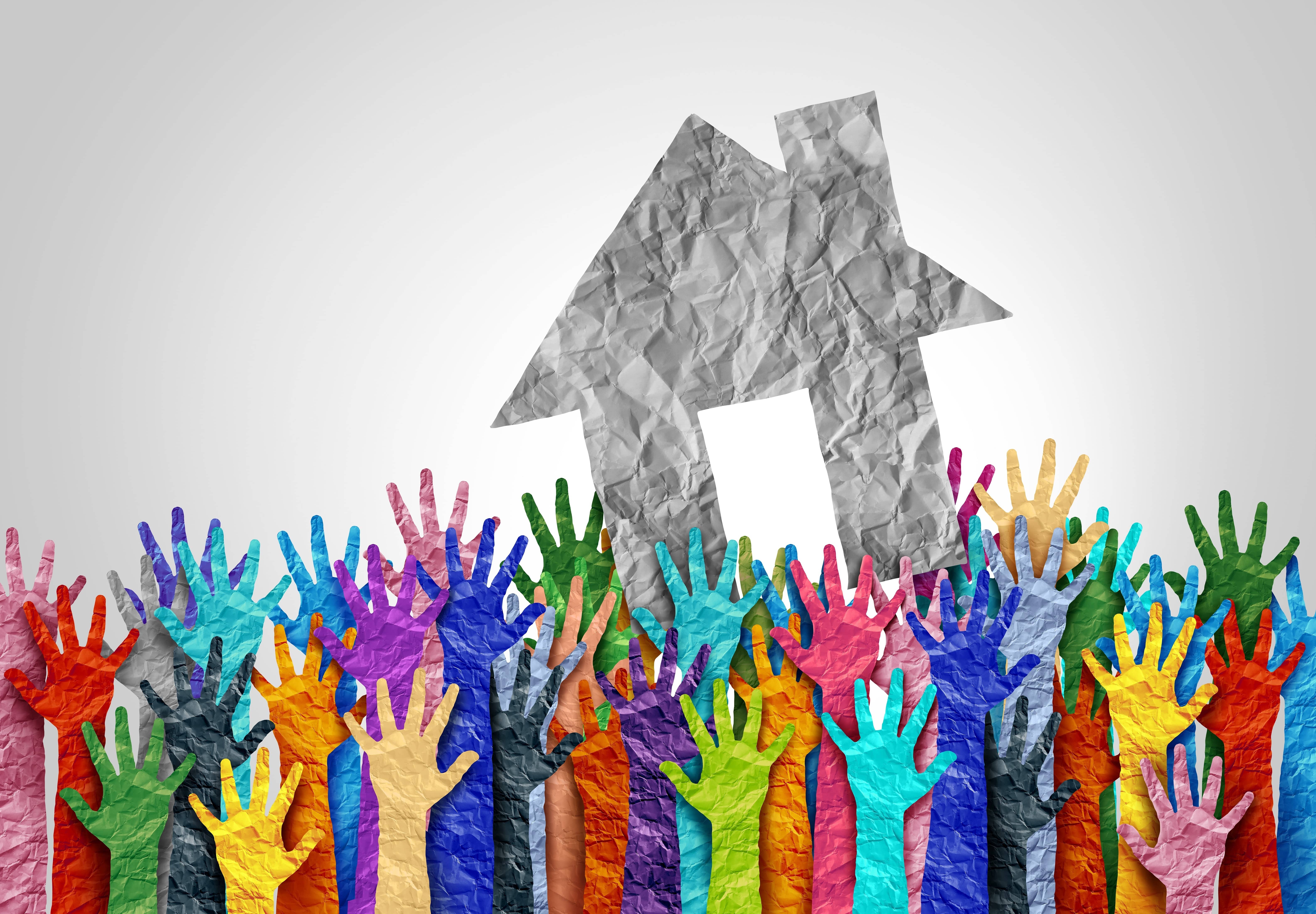 Concept of a paper house and rainbow colored hands raised in teamwork