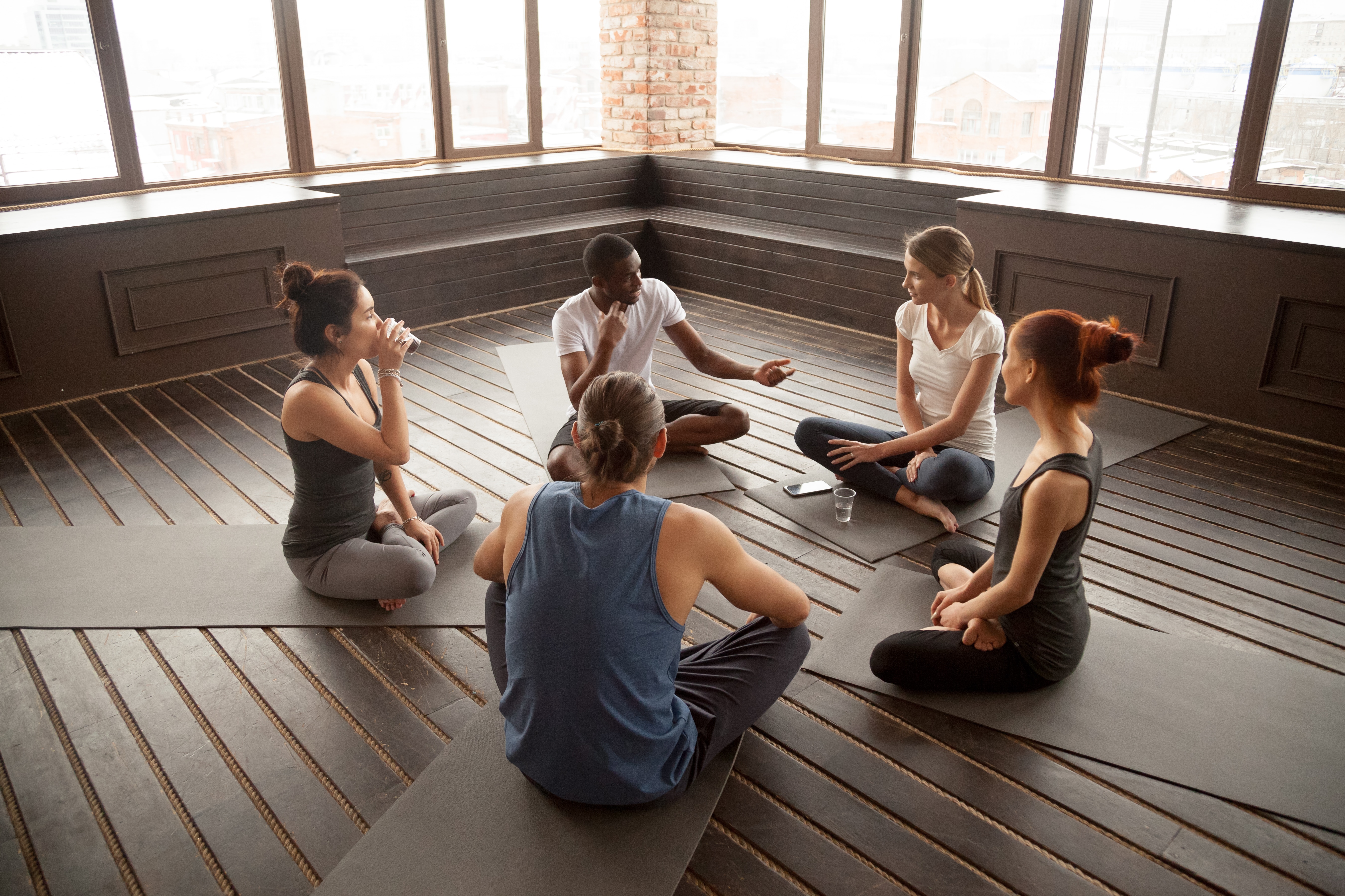 African-American yoga instructor talking to diverse group of people