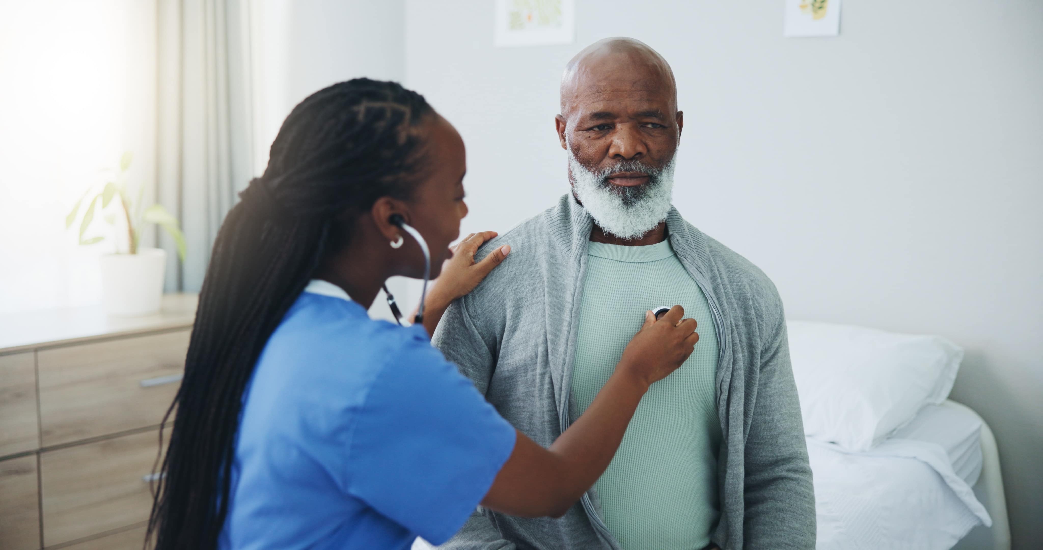 Nurse using a stethoscope to listen to a man's heartbeat