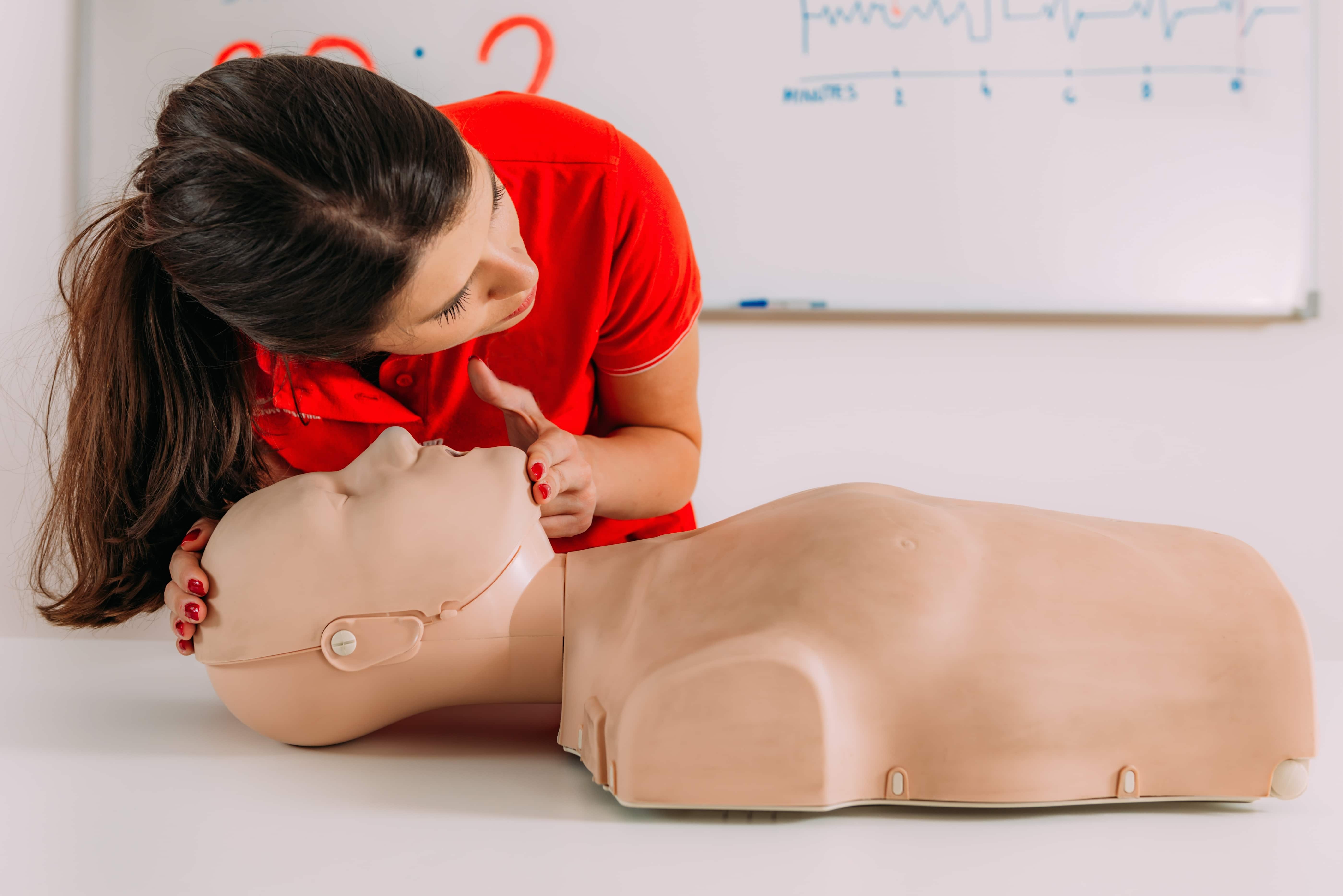 Woman practicing CPR first aid on a medical mannequin