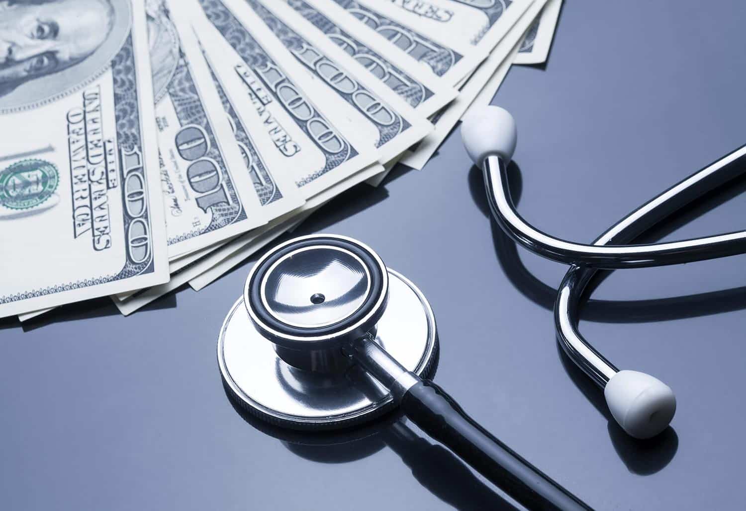 Close up of a stethoscope and hundred dollar bills